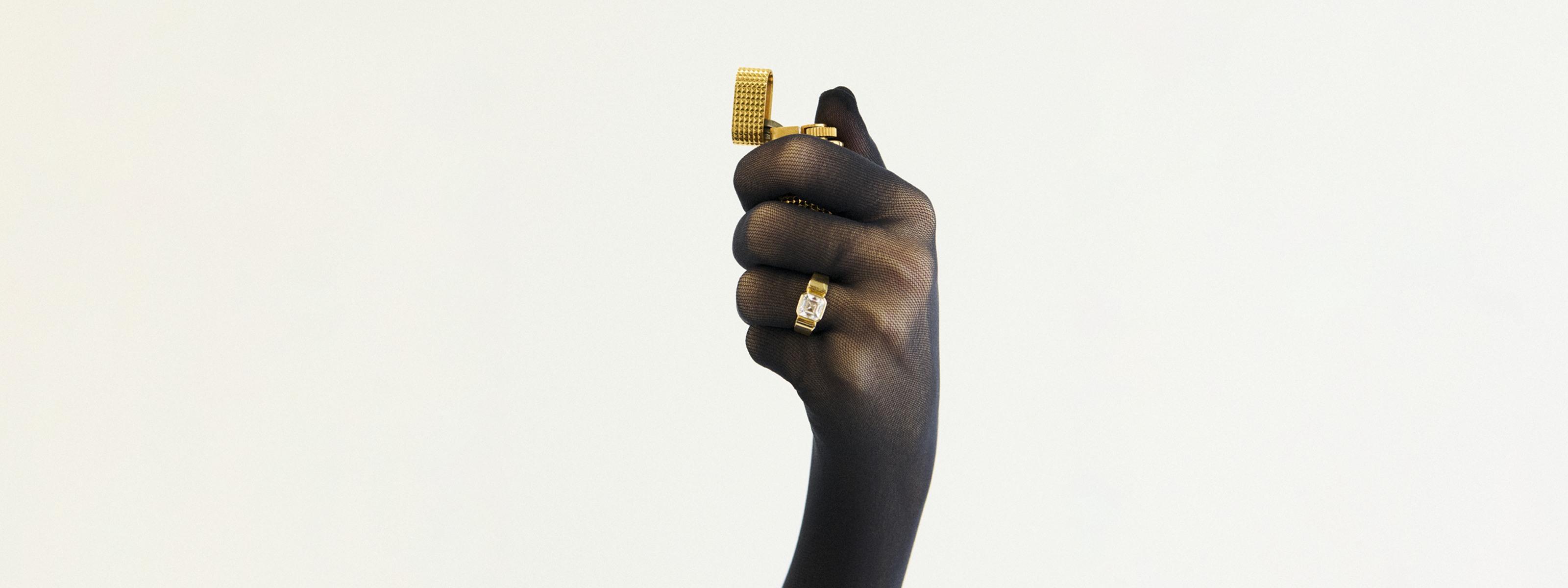 Hand holding a gold ring against a white background